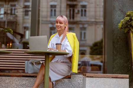 Joyful woman working on laptop at outdoor cafeの写真素材