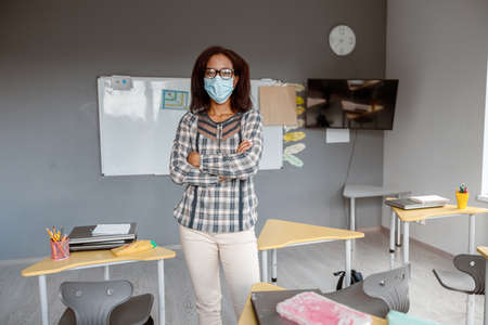 Afro American woman with arms crossed wearing protective maskの写真素材