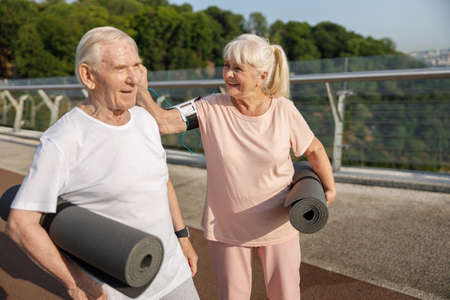 Mature woman puts earphone pad into partner ear ready for workout on footbridgeの写真素材