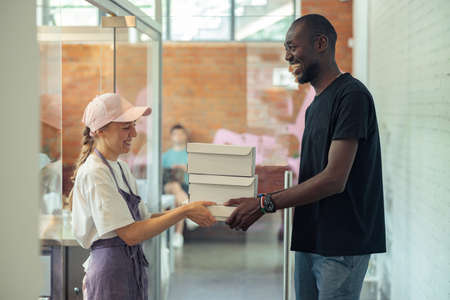 Happy woman and man with black skin speaking in the corridorの写真素材