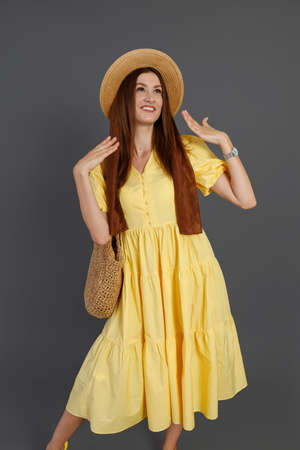 Pretty woman in yellow dress standing in studioの写真素材