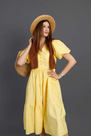 Charming woman in yellow dress standing in studioの写真素材