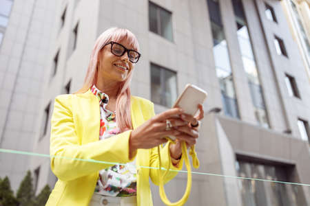 Cheerful young woman using mobile phone outdoorsの写真素材