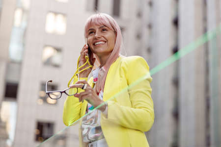 Joyful young woman talking on cellphone outdoorsの写真素材