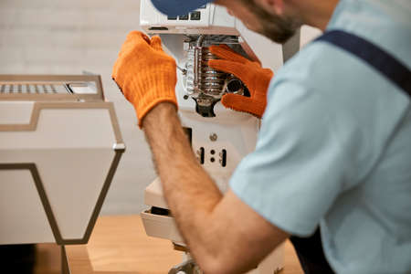Repairman hands fixing coffee machine in cafeの写真素材