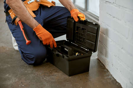 Male electrician in work gloves using tool boxの写真素材
