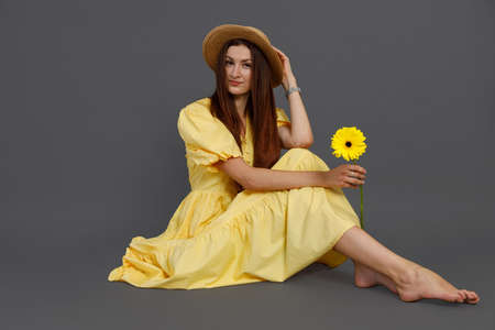 Charming woman with flower sitting on the floor in studioの写真素材