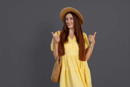 Attractive woman in yellow dress giving thumbs upの写真素材