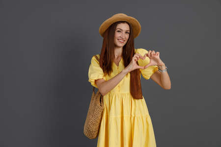 Charming woman in yellow dress showing heart signの写真素材