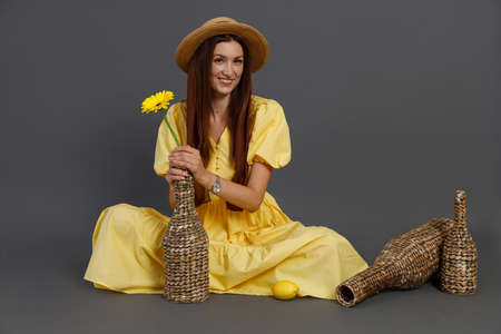 Charming woman in yellow dress sitting on the floor in studioの写真素材