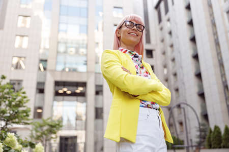 Proud lady with folded arms watching something before her outdoorsの写真素材