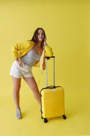 Pretty woman with travel bag standing in studioの写真素材