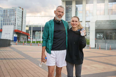 Portrait of two active middle aged sportive people in sportswear walking together outdoors after gym workoutの写真素材