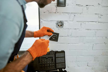 Man hands fixing electrical wall socket with screwdriverの写真素材
