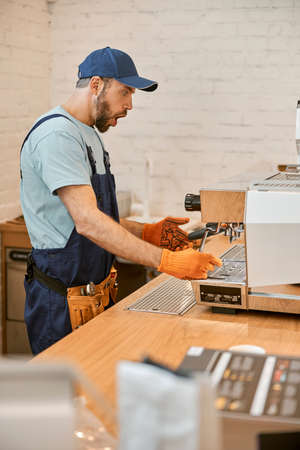 Shocked repairman fixing coffee machine in cafeの写真素材