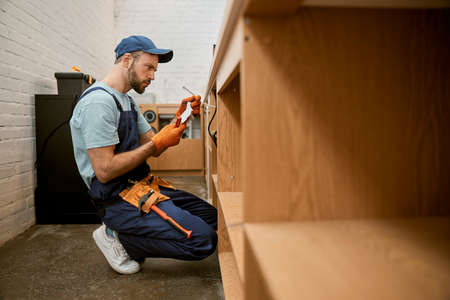 Serious male electrician repairing desk electrical wires
