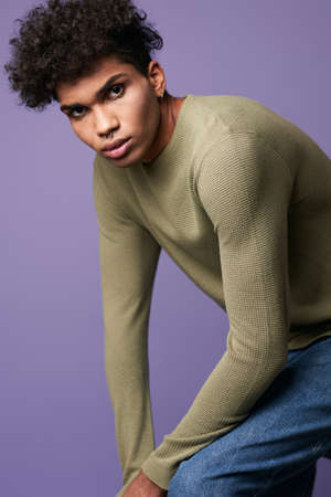 Young transgender man sits in t-shirt and blue jeans verticale portrait. Sensual trans gender maleの写真素材