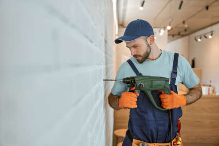 Bearded man drilling wall with hammer drillの写真素材