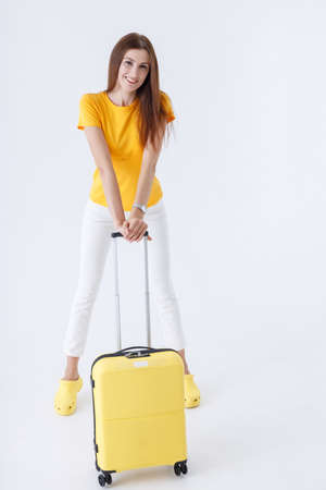 Beautiful woman with travel bag standing in studioの写真素材