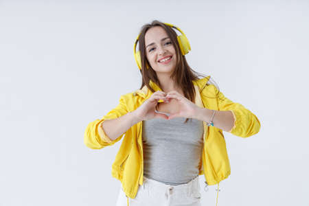 Beautiful young woman in headphone showing heart signの写真素材