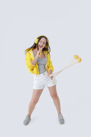 Cheerful woman listening to music and singing into smartphoneの写真素材