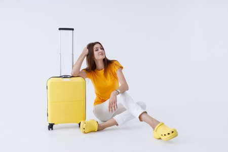Charming female traveler sitting near trolley luggage bagの写真素材