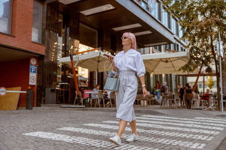 Cheerful young woman crossing the road on the streetの写真素材
