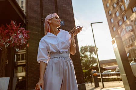 Cheerful young woman listening to music on the streetの写真素材