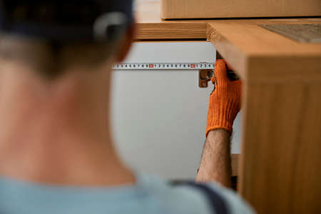 Male hand measuring cupboard door in kitchenの写真素材