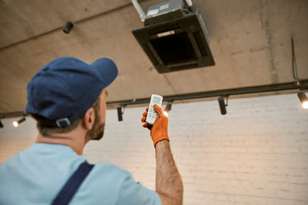 Male worker checking air conditioner in restaurantの写真素材