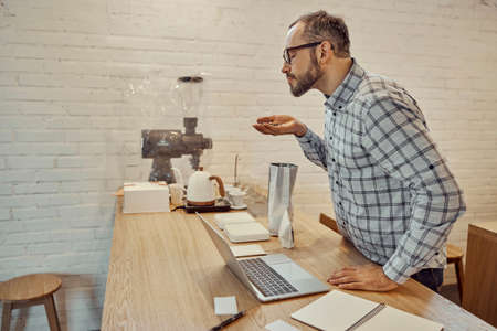 Bearded man smelling coffee beans in cafeの写真素材