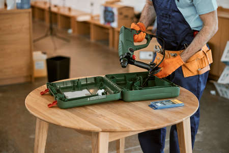 Male builder in gloves holding electric hammer drillの写真素材