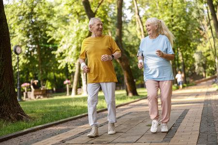 Positive senior family couple run tgether along road in parkの写真素材