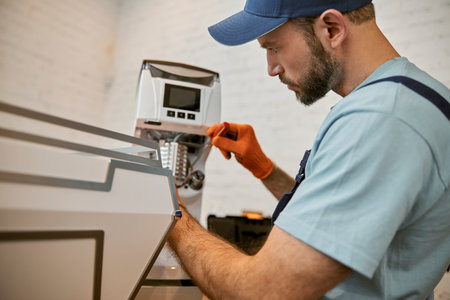 Bearded repairman fixing coffee machine in cafeの写真素材