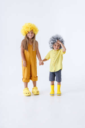 Adorable little girl and boy standing hand in hand in studioの写真素材