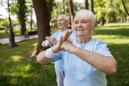 Smiling mature lady with partner practice Chikung together in green city parkの写真素材