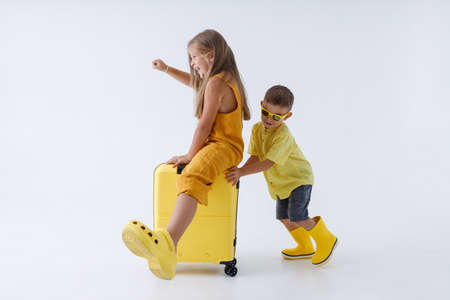 Adorable little boy giving his sister ride on travel suitcaseの写真素材