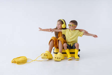 Adorable little girl and boy sitting on travel bagの写真素材