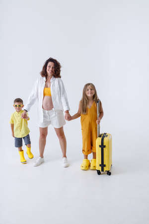Joyful pregnant woman and her kids standing in studioの写真素材