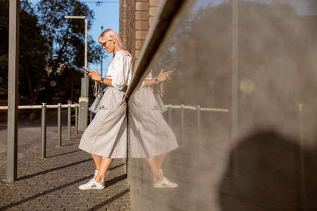 Joyful young woman using mobile phone on the streetの写真素材