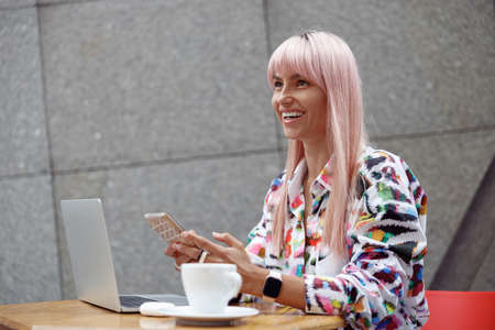Happy female with mobile phone sitting outsideの写真素材