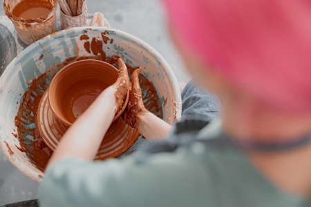 Woman potter sculpting dish from clay lump in atelierの写真素材