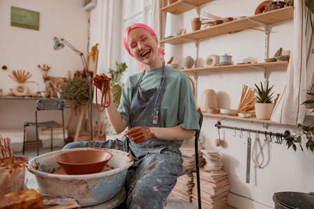 Young female master working with clay in pottery roomの写真素材