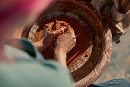 Female potter shaping clay on pottery wheel in atelierの写真素材