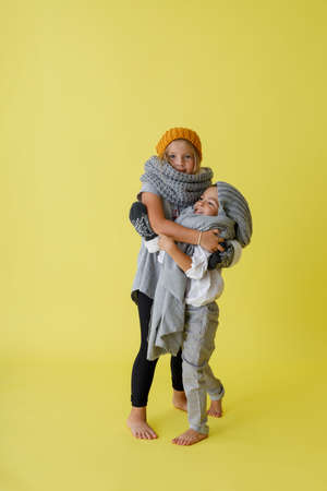 Adorable kids in knitted hats hugging in studioの写真素材