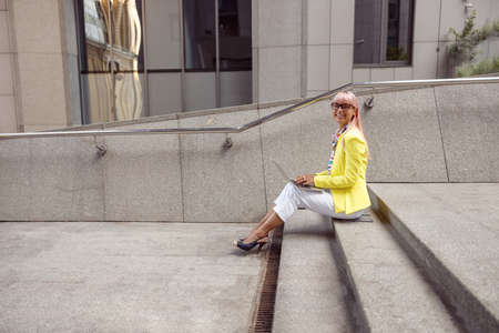 Lady on stairs smiling to camera during work with laptopの写真素材