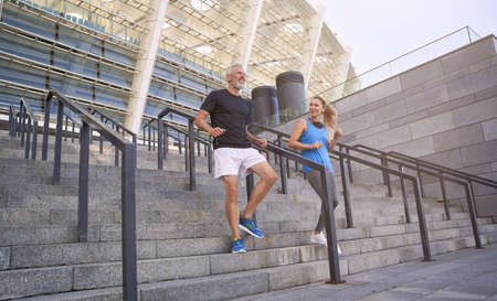 Mature couple, man and woman in sportswear making a workout session together, exercising on staircase outdoorsの写真素材