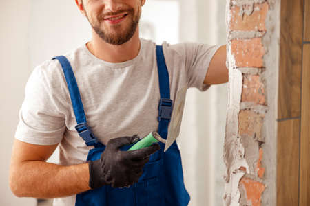 Cropped shot of worker or craftsman using spatula and plastering old cement wall with puttyの写真素材