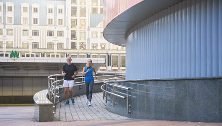 Active middle aged couple in sportswear running together in the city in the morningの写真素材