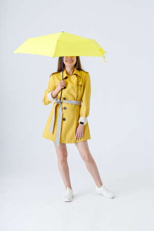 Cheerful young woman with umbrella standing in studioの写真素材